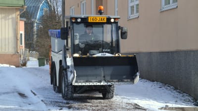 Juuso Sahlberg kör en liten traktor som sandar en trottoar