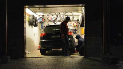 Sami Laakkonen tittar på då Akseli Laakkonen byter däck på bilen, inne i garaget.