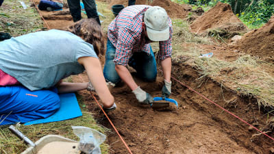 En man och en kvinna gräver vid en arkeologisk utrgrävning.