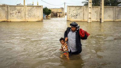 En iransk man bär sin son i staden an Ahvaz, Iran. 