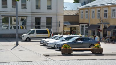 Taxibilar parkerade i en rad på ett torg.