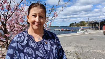 En kvinna i blå kläder står vid ett blommande körsbärsträd, hon heter Harriet Sundqvist-Mendez.