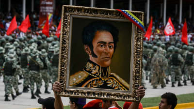 Publiken bar fram ett porträtt på nationalhjälten Simon Bolivar under fredagens militärparad i Caracas. 