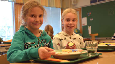 Eleverna Liv Svartsjö och Clara Åbrendt i Gerby skola äter lunch vid sina pulpeter.
