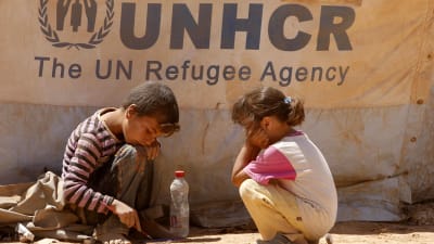 Två barn framför UNHCR:s banderoll.