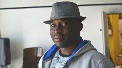 porträtt av francis oyeyiola. han bär en grå hatt, en grå tröja och tittar in i kameran.