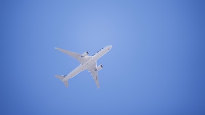 Ett vitt flygplan fotograferat nerifrån mot en bakgrund av blå himmel. Det är ett Finnairplan som flyger över Böle i Helsingfors i juni 2020.