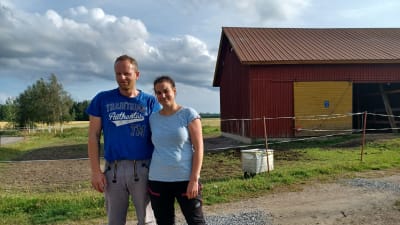 Ett par i t-skjortar framför en ladugård