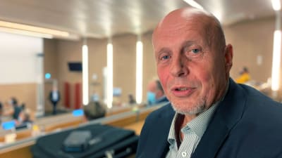 En skallig man tittar mot kameran