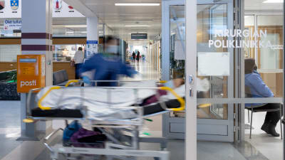 Patient i sjukhussäng rullas in genom en dörr på sjukhus. 