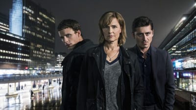 Seriens tre huvudpersoner iförgrunden med en nattmörk stad i bakgrunden.