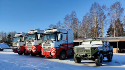 Ett militärfordon och tre dragbilar till lastbilar står bredvid varandra på en gårdsplan.