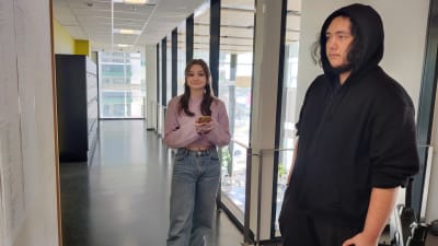 En ung kvinna och man står i en skolkorridor. De heter Emelie Lindberg och Niclas Grönqvist.