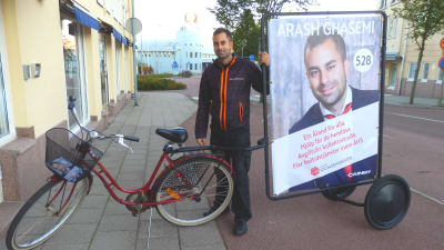 Socialdemokraternas kandidat Arash Ghasemi saknar åländsk hembygdsrätt och kan därför kandidera endast i stadsfullmäktigevalet i Mariehamn. Kampanjfordonet är cykeln.