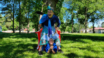 En man och en kvinna utklädda till städerskor i en lummig park.