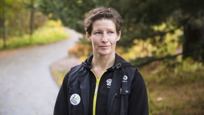 Porträttbild av Sanna Hellström på en asfalterad väg i skogen.