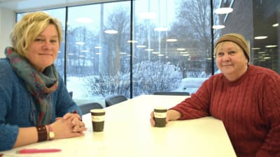 Regina Ekblom och Camilla Gorbatow sitter vid ett bord och dricker kaffe.