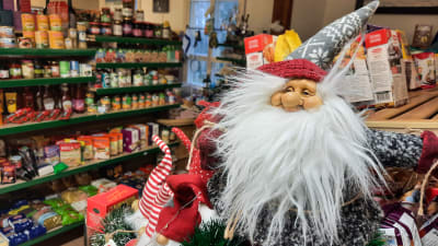 Till vänster syns en butikshylla med olika produkter på, till höger närmare i bild en jultomte.