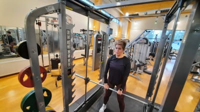 En kvinna i träningskläder lyfter vikter på ett gym.