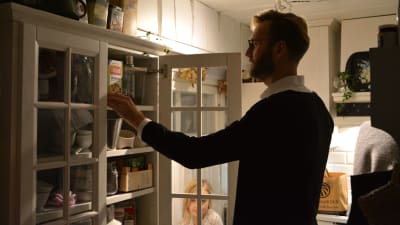 Jan- Christian Forsman sätter matvaror in i vita köksskåp
