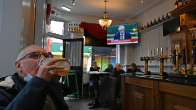 En man sitter på en pub i Liverpool och dricker ur ett stort ölglas.