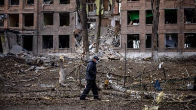 En man i munskydd får förbi en förstörd byggnad i Vasylkiv nära Kiev.