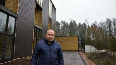 Man vid hus i skogsmiljö.