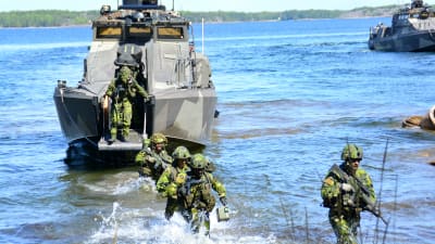 svensk militär personal vadar i vatten från båt