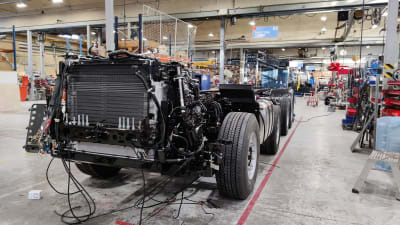 En lastbil håller på att tillverkas i en fabrik, man ser hjulen och underredet på lastbilen.