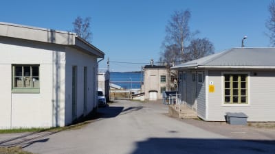 Produktionsbyggnader på sprängämnesfabriken Forcits område i Hangö, med havsutsikt i bakgrunden.