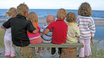 sju barn i olika ålder tittar ut över havet
