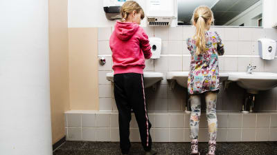Två skolbarn tvättar händerna.