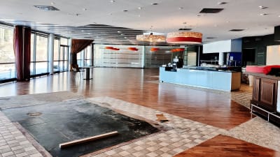 En tom restaurang där det ännu inte finns bord och stolar. En bardisk och lampor i taket syns.