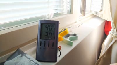 Termometer visar 30 grader vid soligt fönsterbräde och persienner för fönstren.