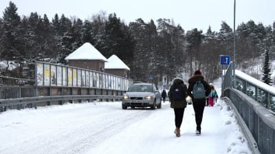 Bilar och fotgängare går på järnvägsbron i Karis en vintrig dag.