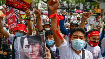 Demonstranter visar upp bilder av den fängslade ledaren Aung San Suu Kyi under en protest utanför FN:s högkvarter i Bangkok i Thailand.