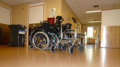 Rullstol och rollator i en sjukhuskorridor.