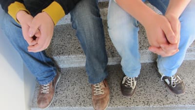 Två killar sitter i trappa i skolan.