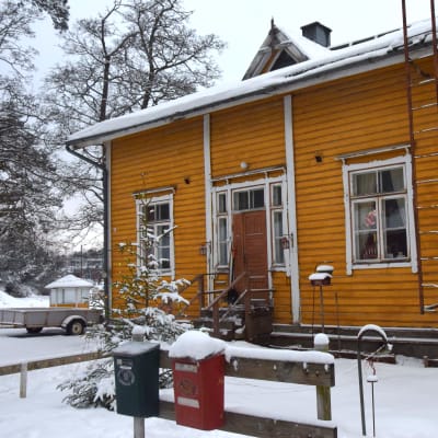 En gul trävilla, gammal arbetarbostad med fler bostäder. Målfärgen flagar, stockarna är ruttna vilket lett till hål i ytterväggarna. Den här delen är ändå i hyfsat skick, det bor en hyresgäst i denna ända av huset.