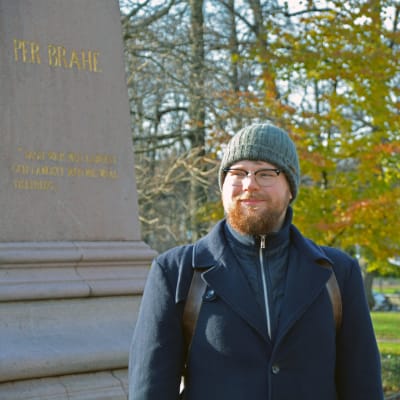 En man står bredvid Per Brahe-statyn nära domkyrkan i Åbo.