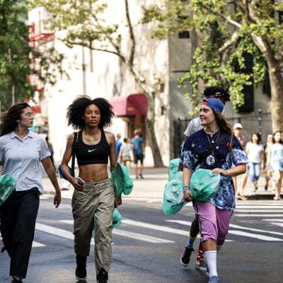 Tre unga tjejer och en ung kille går på en gata i New York bärande på skateboards.