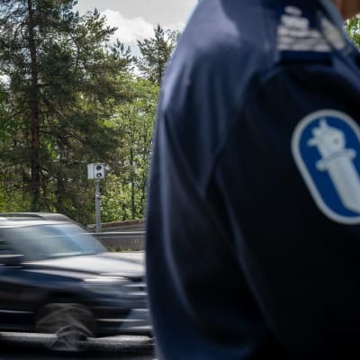 Liikenteen nopeusvalvontakamera eli peltipoliisi eli kameratolppa valtatie 12:lla Lahden Kärpäsenmäellä. Etualalla anonyymi poliisi ja hihamerkki.