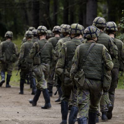 Varusmiehiä marssimassa metsässä.