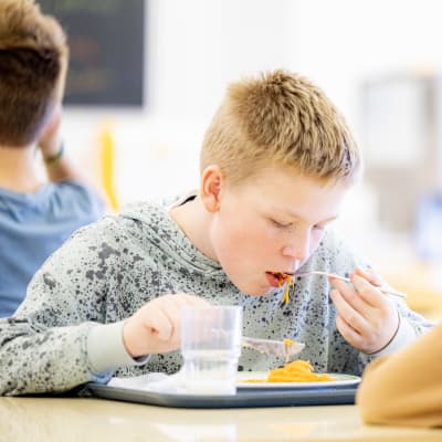 Pojke i grå tröja äter skollunch i Kimito.
