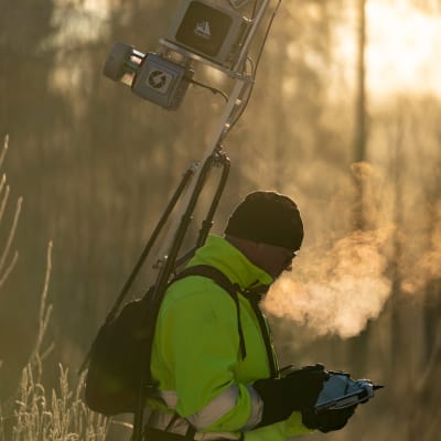 Antero Kukko luotaa reppukeilaimella lähimetsää kovassa pakkasessa auringon noustessa.