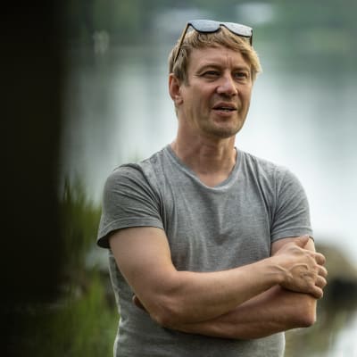 Porträttfoto av man som står nära vatten med en grå t-skjorta