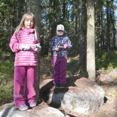 Två flickor står på varsin sten och täljer.