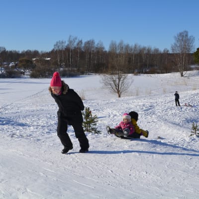 Kvinna drar barn i pulka