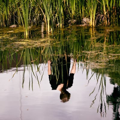 Bilden av en person reflekteras i vattnet.