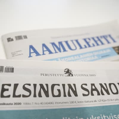 Printversionerna av tidningarna Helsingin Sanomat och Aamulehti på varandra på en vit yta.